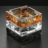 Amber square glass ashtray stacked on clear and gray glass ashtrays