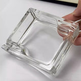 Clear square glass ashtray held in hand showing thick glass design