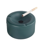 Teal stainless steel ashtray with funnel lid and cigarette on white background