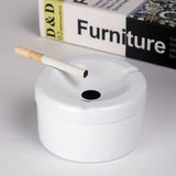 White stainless steel ashtray with funnel lid and cigarette on tabletop