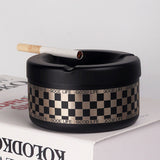 Black “Good Life” checkered ashtray with cigarette on tabletop