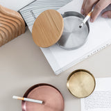 Round stainless steel ashtray with removable wooden lid styled on a table for modern home decor