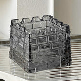 Smoked gray geometric glass ashtray on striped surface