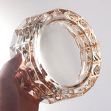 Amber crystal ashtray held up to light, faceted luxury glass ashtray with elegant sparkle