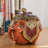 Brown elephant ashtray with lid styled on table with vintage decorative details