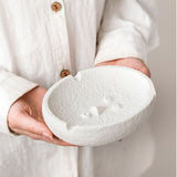 Minimalist face expression ashtray held in hands, showing size and sculpted design