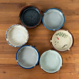 Set of six round ceramic ashtrays in assorted Japanese-inspired colors and patterns with cigarette rests