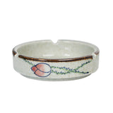 Round cream ceramic ashtray with peach and green pattern, cigarette rests, and glazed finish
