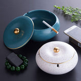 Teal and white lidded ceramic ashtrays with cigarettes placed in the built-in rests