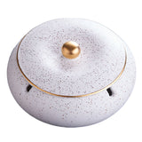 White speckled ceramic ashtray with fitted lid and gold knob on white background