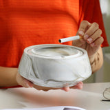 Hand holding marble-style ceramic ashtray with lid