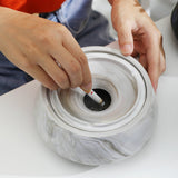 Hands opening and adjusting the lid on ceramic ashtray