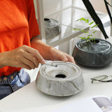 Person cleaning or using marble-style ceramic ashtray on tabletop