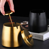 Gold and black windproof stainless steel ashtrays styled on a dark tabletop