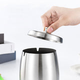 Hand lifting the lid from a silver stainless steel ashtray