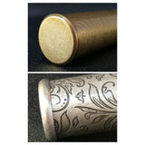 Close-up of engraved metal cigar tube cap and decorative pattern