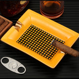 Yellow ceramic cigar ashtray with cigar on dark tabletop