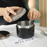Black covered outdoor ashtray with lid being used on a table for a tidy smoking area