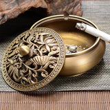 Open palm-sized copper ashtray with carved lid removed, showing the interior