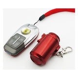 Red can-style metal pocket ashtray beside car key, compact lidded ashtray with keychain