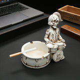 Side view of skull drummer ashtray with cigarette resting across the bowl