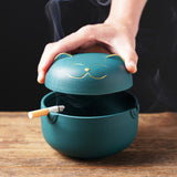 Covered cat ashtray with lid being opened on tabletop