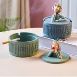 Pretty lady covered ashtray with cigarette resting in blue ashtray base